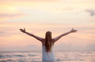 A woman enjoying a serene sunset on Unawatuna Beach, Sri Lanka, depicting peace and freedom.